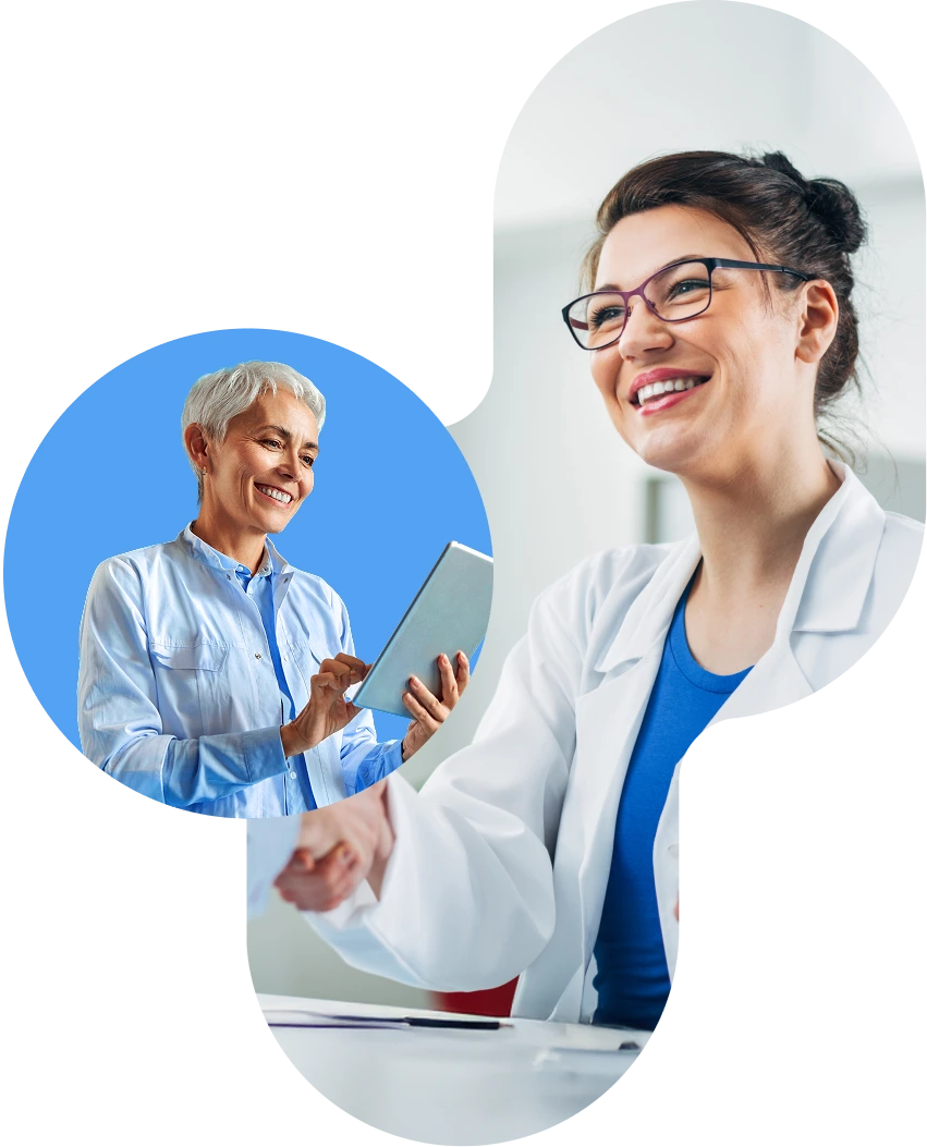 Two smiling female doctors in lab coats, one holding a tablet and the other in conversation