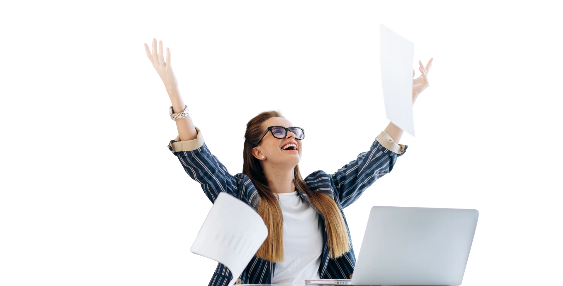 Woman celebrating at desk, throwing papers in the air while smiling in front of a laptop